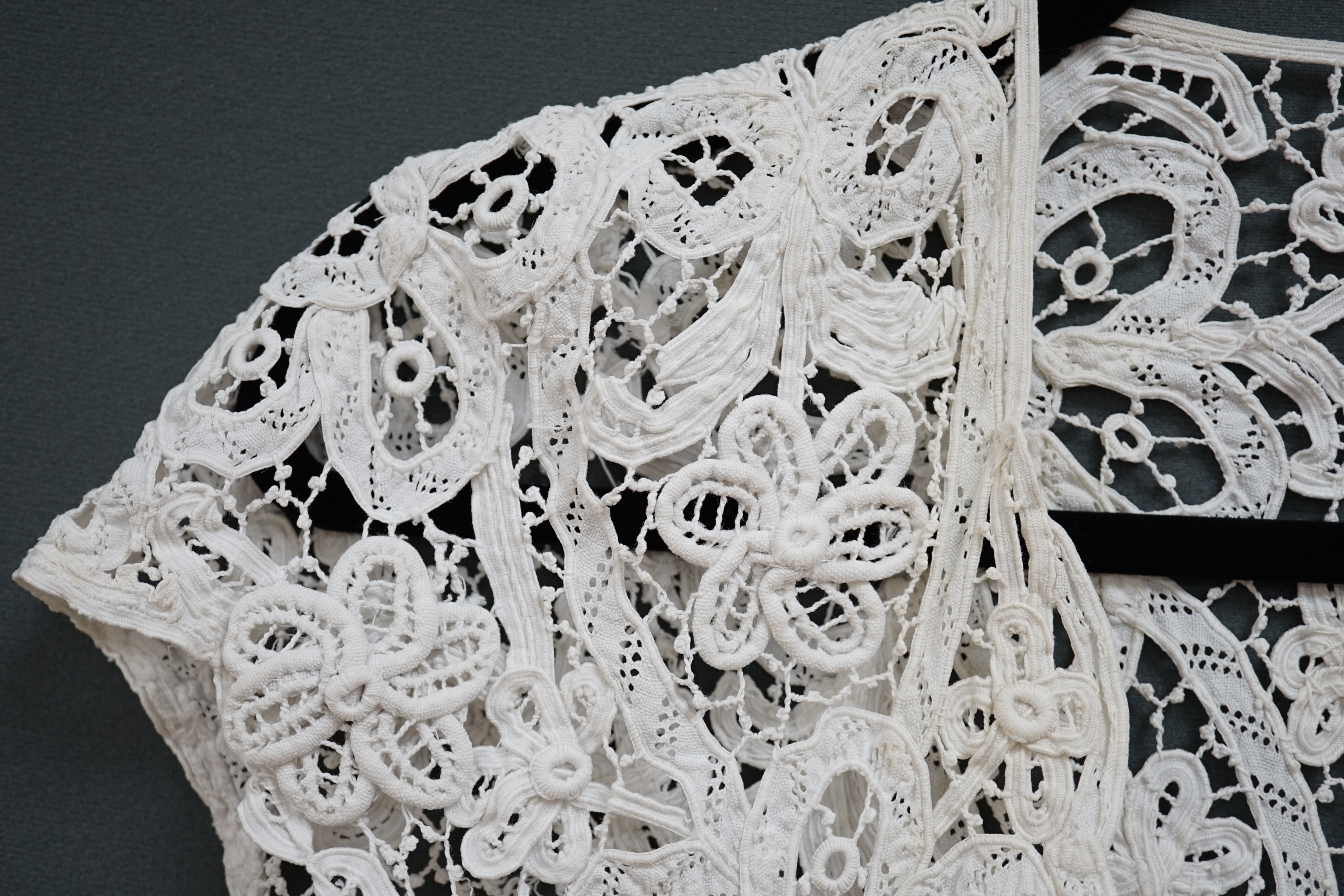 An Edwardian ladies white lace bolero, a tape lace Edwardian cap sleeve bolero with hand sewn bracts, attaching the tape lace together, possibly part of a wedding dress or summer dress, back under arm width 36cm. Conditi